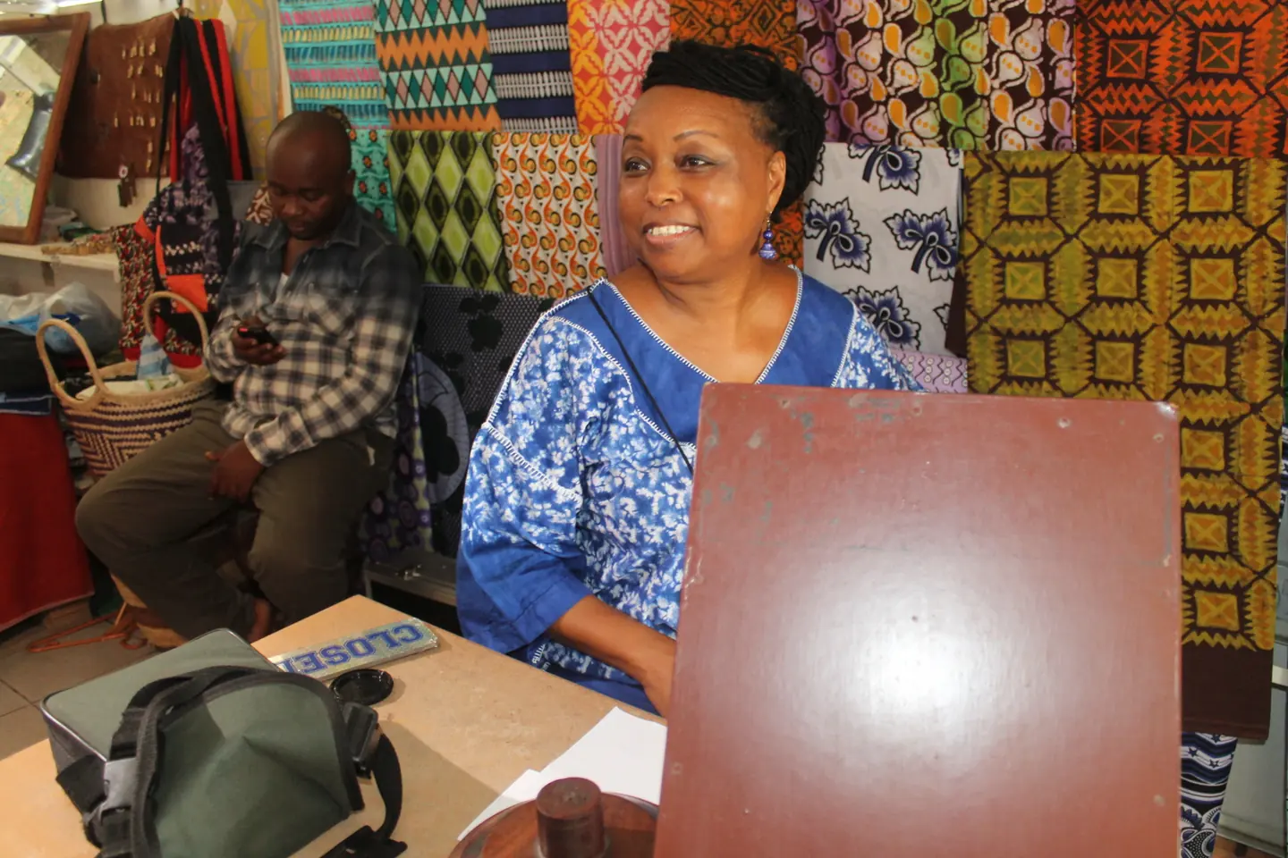A smiling businesswoman at her desk in a fabric design studio in Tanzania.