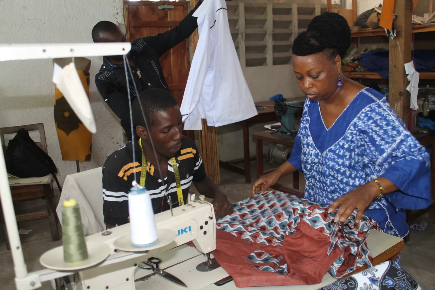 Tailors cutting and sewing fabric at a workshop in Tanzania.
